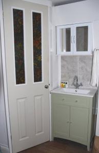 a bathroom with a sink and a white door at 3 Bedroom Cottage minutes walk from town, harbour & Beaches. in St Ives