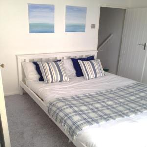 - un lit avec des oreillers bleus et blancs dans une chambre dans l'établissement 3 Bedroom Cottage minutes walk from town, harbour & Beaches., à St Ives