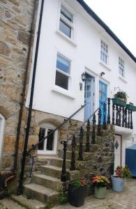 a white house with stairs and a blue door at 3 Bedroom Cottage minutes walk from town, harbour & Beaches. in St Ives