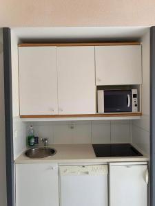 uma cozinha com armários brancos, um lavatório e um micro-ondas em Appartement T2 à Port-Bourgenay Résidence île au pré em Talmont