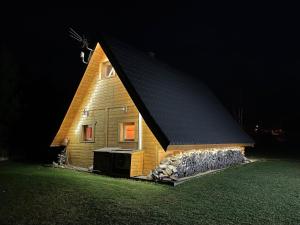 ein kleines Holzhaus mit schwarzem Dach in der Nacht in der Unterkunft ZŁOTEK in Złoty Stok