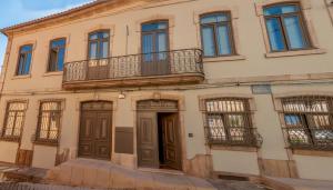 um edifício antigo com uma varanda e uma porta em Cravo’s Heritage House em Pinhel