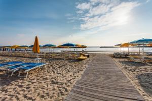 a wooden pathway to the beach with umbrellas and chairs at Hotel Asiago Beach in Lido di Savio