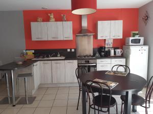 a kitchen with red walls and a table and chairs at Gîte AUX 3 PTITS COCHONS in Cuisiat