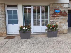 two pots of flowers in front of a door at Gîte AUX 3 PTITS COCHONS in Cuisiat +4 photos