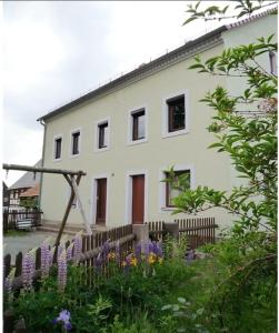 une maison blanche avec des fleurs devant elle dans l'établissement Guesthouse Elbsandstein App. Bastei, à Rathmannsdorf