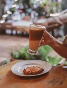 a person holding a glass of coffee and a plate of food at Posada Maná in San Juan La Laguna