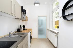 a kitchen with white cabinets and a sink and a window at The Koburger II - central budget studio with extra high bed, Ideal for families & kids or couples in Berlin
