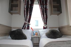 a bedroom with two beds and a window at Perran Sands Perranporth in Perranporth