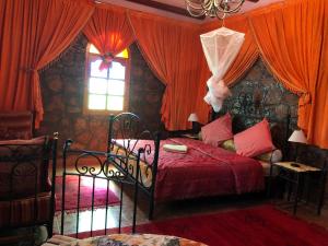 een slaapkamer met een bed met rode gordijnen en een raam bij Villa Siliya maga Cœur vallée amlen tafraout in Tafraoute