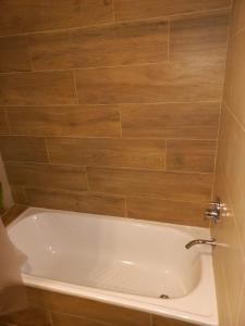 y baño con bañera y pared de madera. en DEPTO NUEVO CON PILETA EN NUÑEZ en Buenos Aires