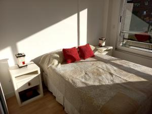 um quarto com uma cama com almofadas vermelhas e uma janela em DEPTO NUEVO CON PILETA EN NUÑEZ em Buenos Aires