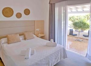 a bedroom with a white bed and a large window at Roquetes Bungalows Premium - Formentera Break in Es Pujols