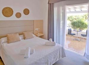 ein Schlafzimmer mit einem weißen Bett und einem großen Fenster in der Unterkunft Roquetes Bungalows - Formentera Break in Es Pujols