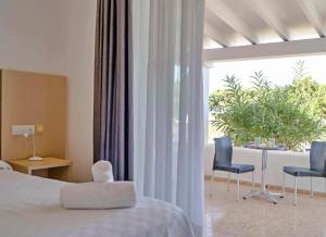 a bedroom with a bed and two chairs and a window at Roquetes Bungalows Premium - Formentera Break in Es Pujols
