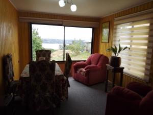 a living room with two chairs and a table and a window at Cabaña la raspa in Castro