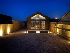 uma casa com luzes de lado à noite em The Potting Shed em Bredon