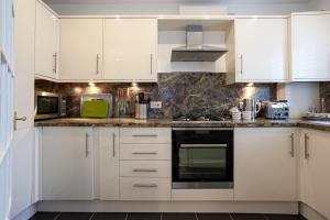 uma cozinha com armários brancos e um aparelho verde em Keswick Ground floor apartment with parking em Keswick