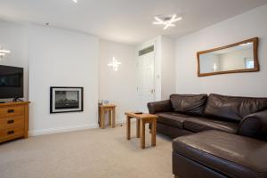 a living room with a leather couch and a television at Keswick Ground floor apartment with parking in Keswick