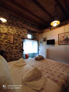 1 dormitorio con 1 cama grande frente a una pared de ladrillo en Bayiri Petit Pension, en Litóchoron