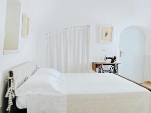 a white bedroom with a bed and a table at Trullo Santangelo in Ceglie Messapica