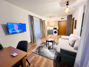 a living room with a couch and a tv on a wall at Pirin Golf Hotel Private Studios - Sani, Bansko in Razlog