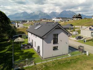 ein weißes Haus auf einem Hügel mit Bergen im Hintergrund in der Unterkunft Apartmán Milbach in Mlynica