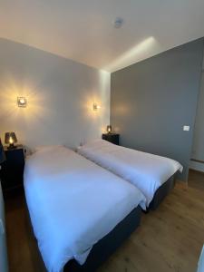 una camera con due letti con lenzuola bianche di Appartement Fr Gilkens Ostende a Ostenda