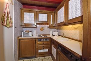 uma cozinha com armários de madeira e um lavatório em Teegelii Hof Rote Syltrose Teegelii Hof em Tinnum
