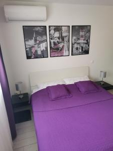 a bedroom with a purple bed with pictures on the wall at Sea Gate Studio in Zadar