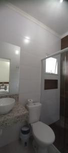 a white bathroom with a toilet and a sink at Moriá Flats in Ubatuba