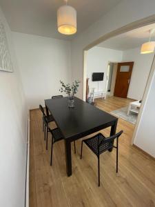 - une table à manger et des chaises noires dans le salon dans l'établissement Appartement dans un beau quartier à Anderlecht, à Bruxelles