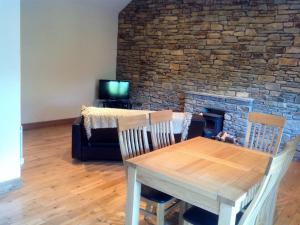 Little Glebe Cottage في Durrus: غرفة طعام مع طاولة ومدفأة من الطوب