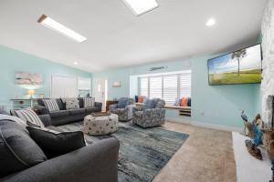 uma sala de estar com um sofá e cadeiras e uma televisão em Dolphin Cove em Palm Coast