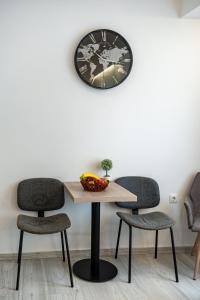 een tafel met twee stoelen en een klok aan de muur bij White & Gray apartment in Rethimnon