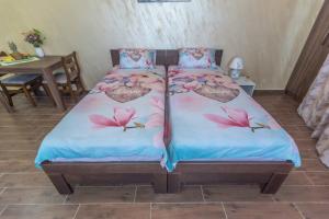 a bed with pink flowers on it in a room at Drina apartman in Banja Koviljača