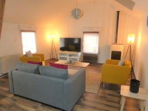 Una sala de estar con un sofá y sillas y un televisor. en LE STRASBOURG - Confortable maison de ville, en Belfort