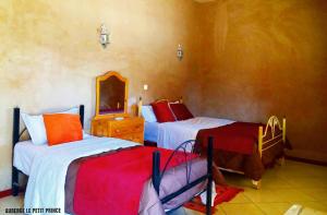 a bedroom with two beds and a mirror at Hotel Riad Le Petit Prince in Merzouga