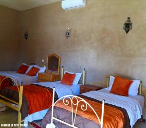 a bedroom with two beds and a mirror at Hotel Riad Le Petit Prince in Merzouga