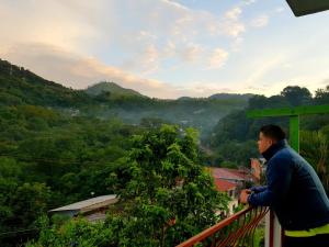 Un uomo in piedi su un balcone che guarda una valle di Casa “Doña Zoyla” B&B a Rovine di Copán