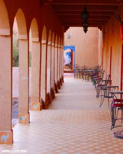 an empty hallway with tables and chairs in a building at Hotel Riad Le Petit Prince in Merzouga