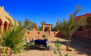 a patio with a table and chairs in a courtyard at Hotel Riad Le Petit Prince in Merzouga