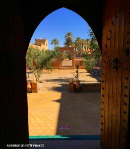 an archway leading to a courtyard with trees and buildings at Hotel Riad Le Petit Prince in Merzouga