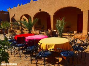 a group of tables and chairs in front of a building at Hotel Riad Le Petit Prince in Merzouga
