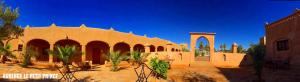 a building in a desert with trees and plants at Hotel Riad Le Petit Prince in Merzouga
