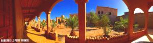a courtyard with palm trees and a building at Hotel Riad Le Petit Prince in Merzouga