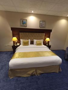 a large bed in a hotel room with two lamps at Saryet Al Hamra Hotel Apartments in Jeddah