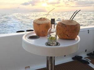 two coconuts and a bottle on a table on a boat at Eden Island Maison 78 (Private Pool) in Eden Island
