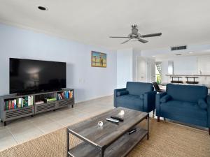 a living room with two blue chairs and a flat screen tv at Surf Villa 626, 1 Bedroom, Beach Front, WiFi, Sleeps 4 in Ponte Vedra