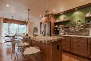 a kitchen with wooden cabinets and a counter with stools at High Loop in Ruidoso +31 photos